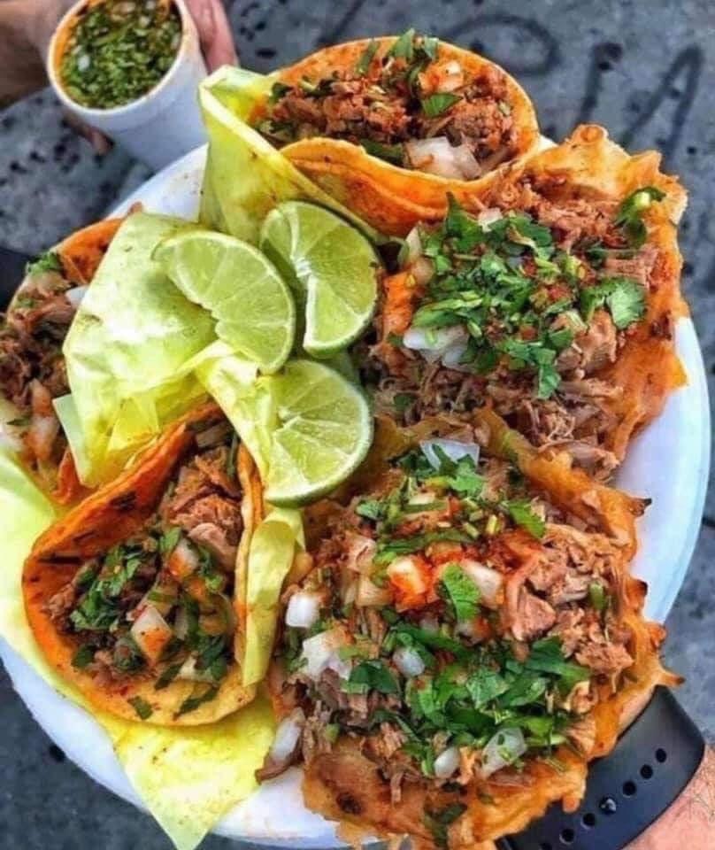 A plate of tacos with limes.